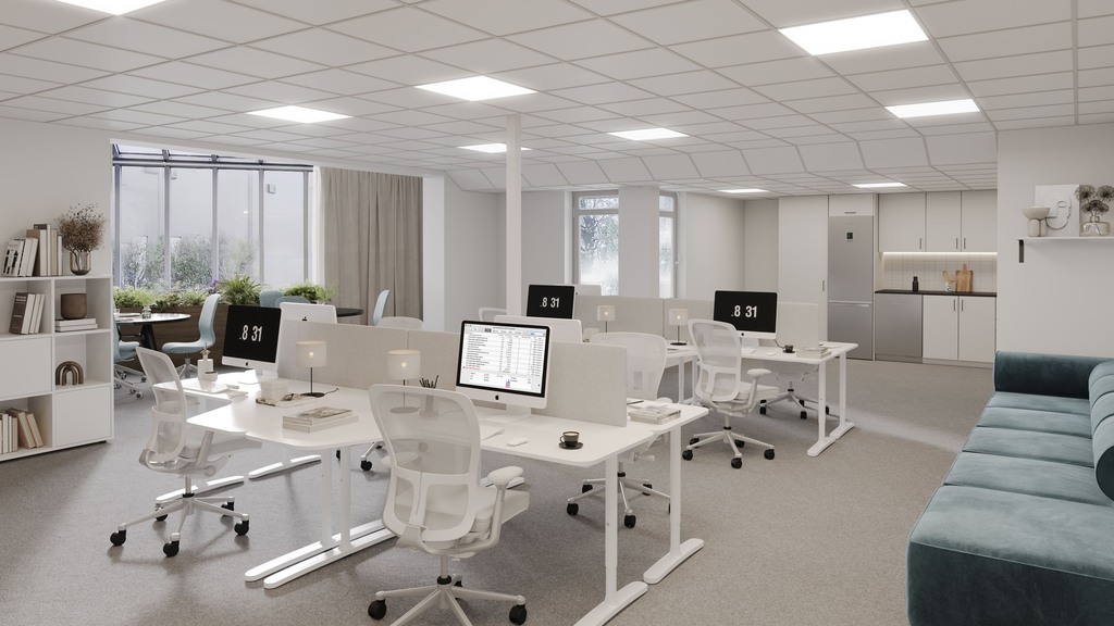 Ljust kontor med konstorsbord, datorer och en mörkgrön soffa