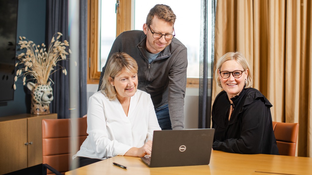 Glada personer samlas runt en dator