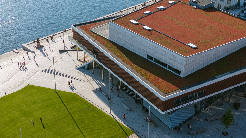 Bild på byggnad precis bredvid vattnet med litet grönområdet 