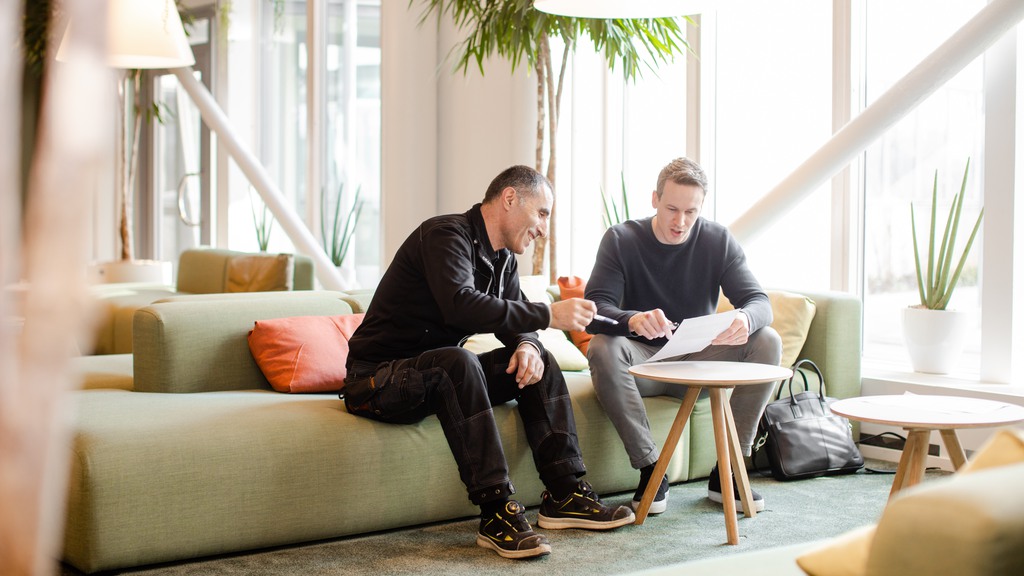 Fastighetsvärdar sitter på en grön soffa i entren till en fastighet på Ideon i Lund. 