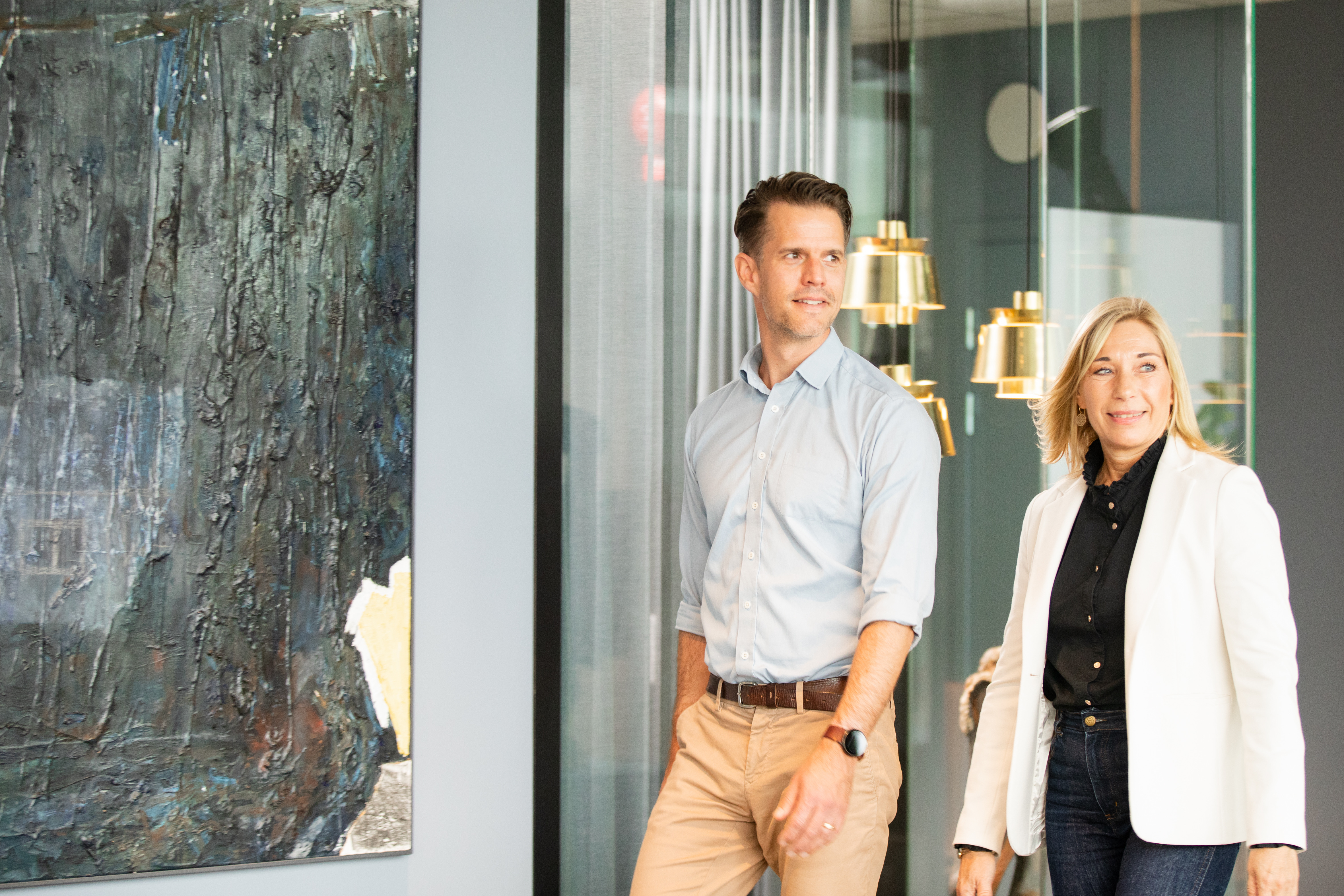 Två kollegor går i korridoren på kontoret och ser glada ut