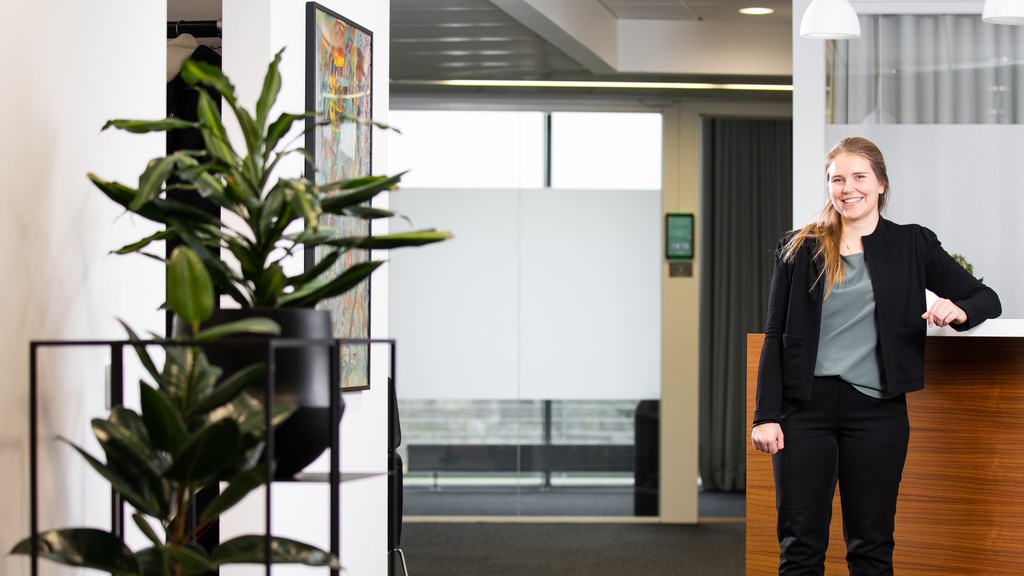 Glad person som står och lutar sig mot en reception