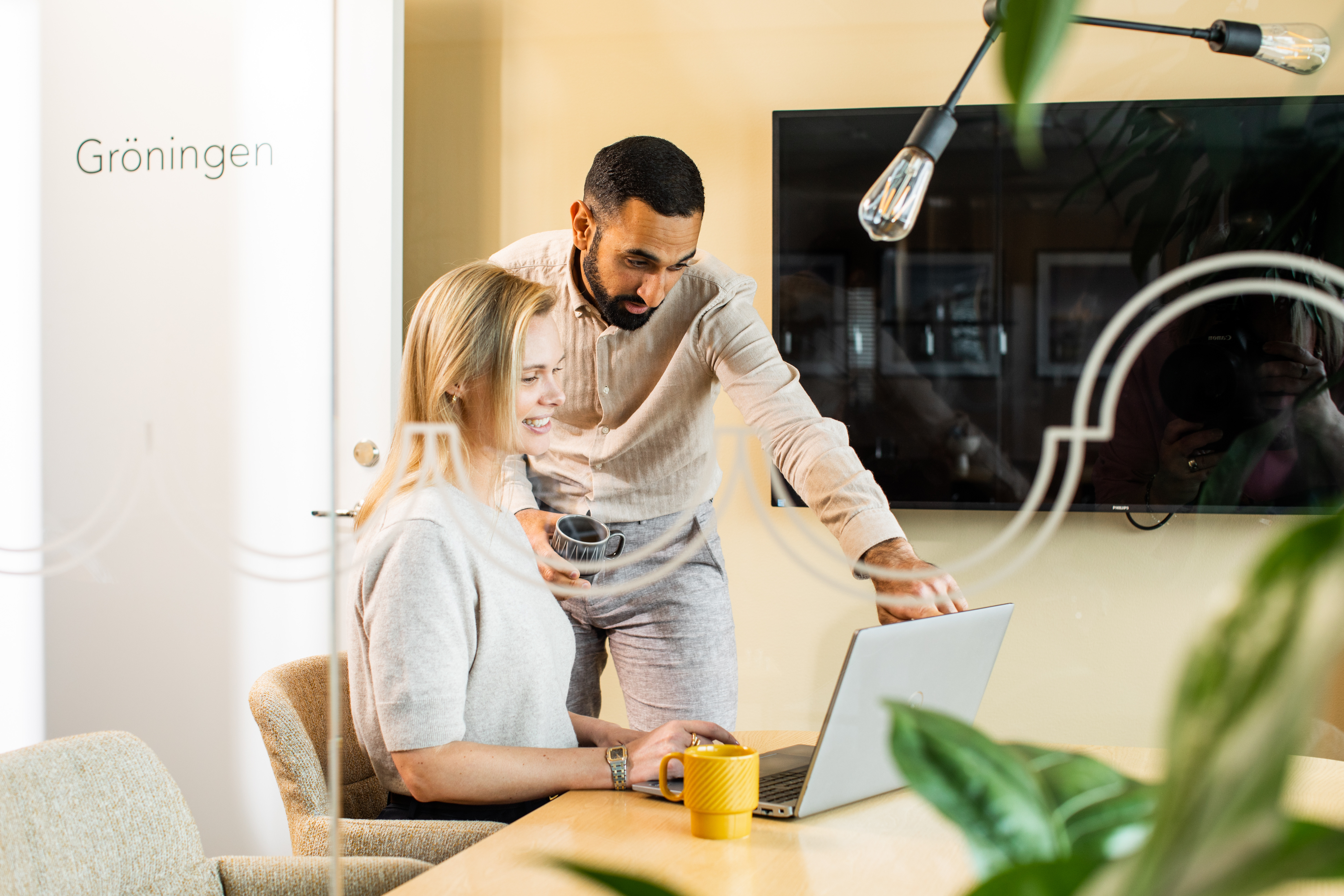 Två personer sitter runt ett bord och tittar på en dator.