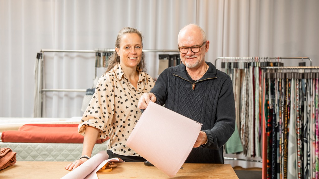 Lotta, grundaren till Casalo, och hennes kollega står i butiken framför färggranna tyger. 