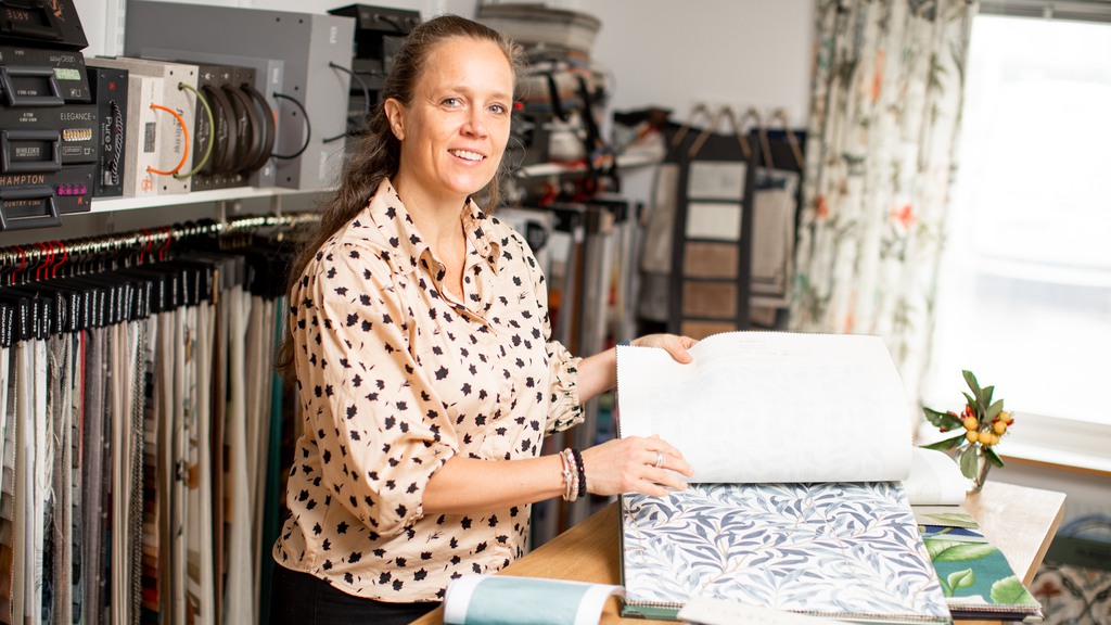 Lotta i Casalos lokaler i Limhamn bläddrar i en bok med tapeter.