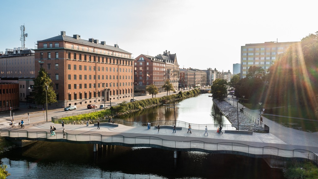 Fastigheten Sparven 15 med rött tegel och en kanal framför, där det är en person som paddlar. 