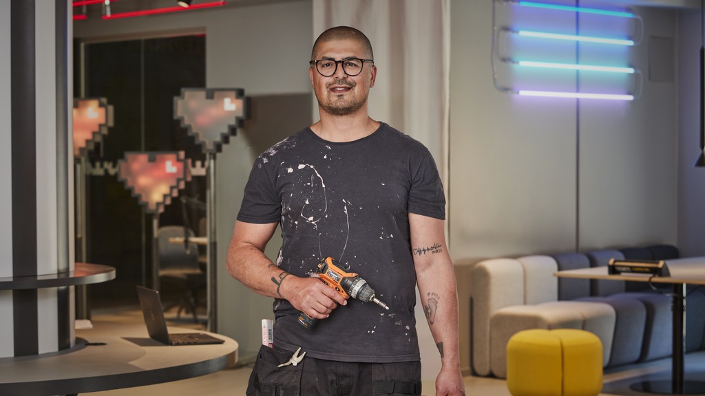 Man klädd i svarta kläder håller en skruvdragare i ena handen och ska föreställa en hemmasnickare