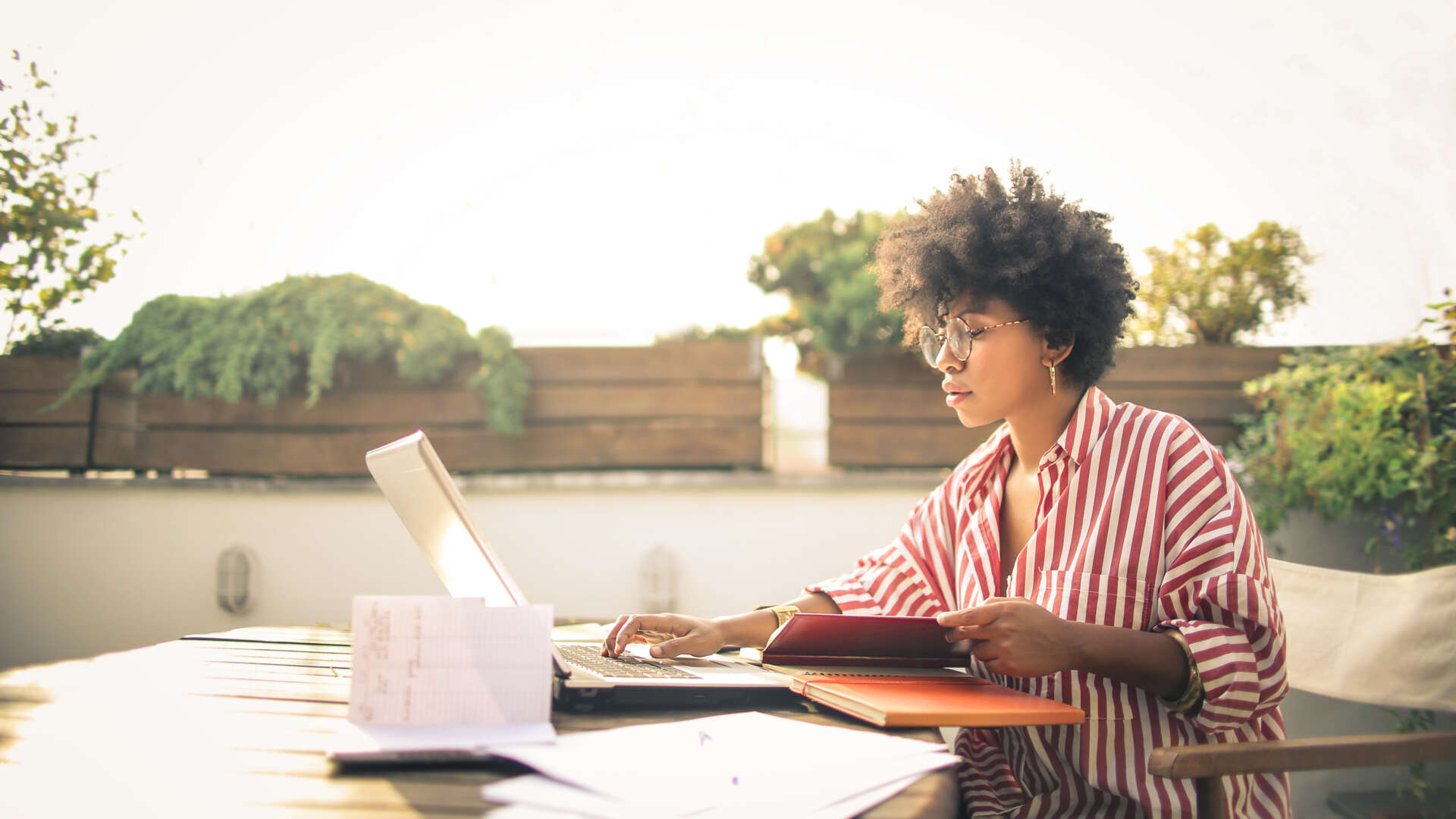 Kvinna som arbetar på en takterass i solen.