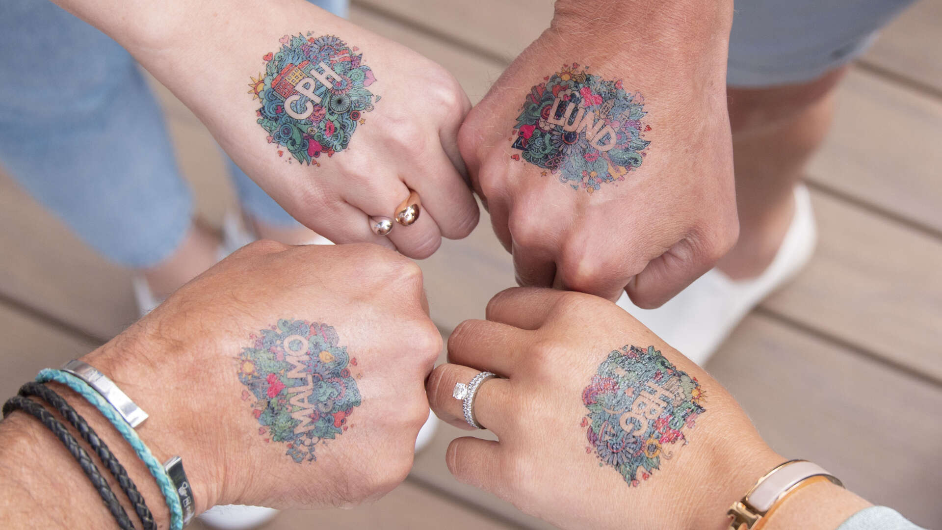 Fyra händer med fusktatueringar där det står Malmö, Lund, HGB och CPH.