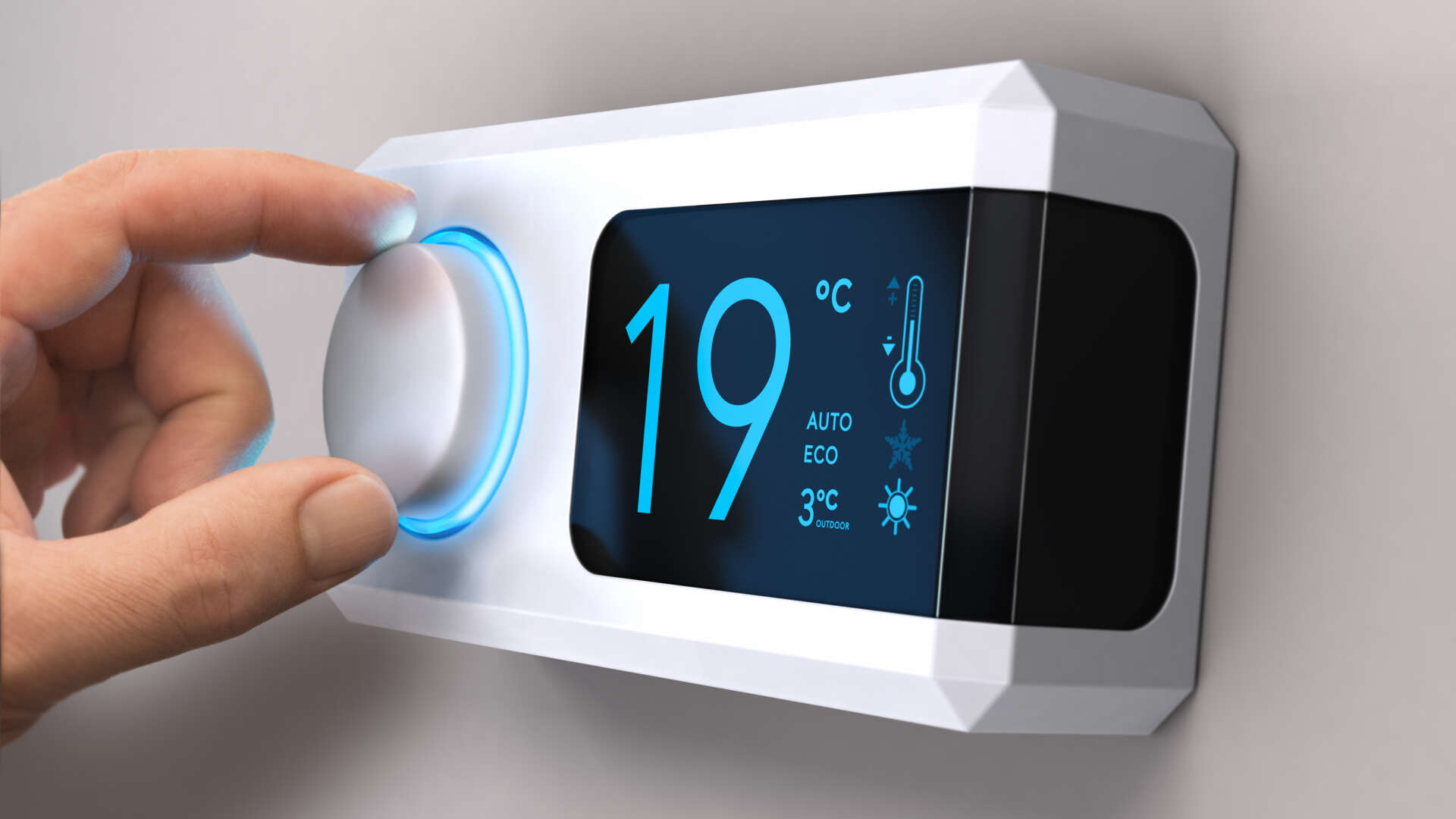 En hand som vrider på en termostat i en byggnad.