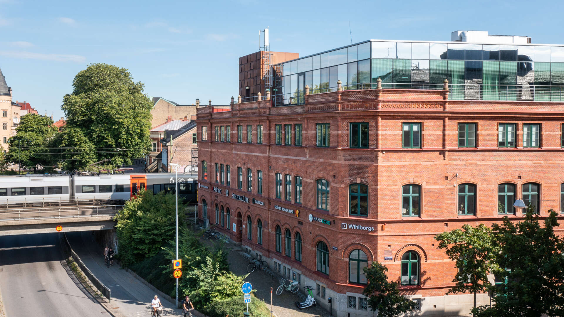 Tegelfastigheten Armaturen med takterass överst. Ett tåg passerar över en vägtunnel i bakgrunden.